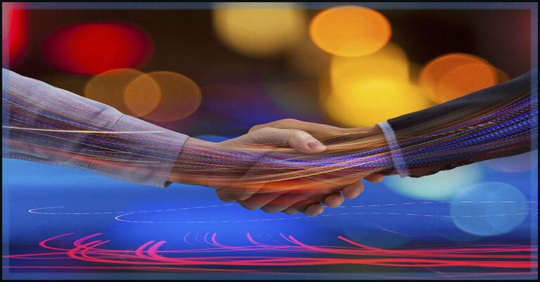 two caucasian business professional handa are depicted shaking on a business deal over a blurred background of tech cconnection imagery