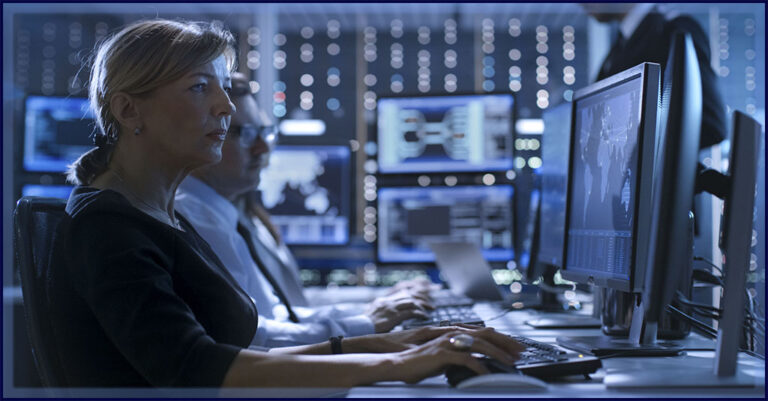 blonde Caucasian woman analyst types on a keyboard in a room full of screens of data